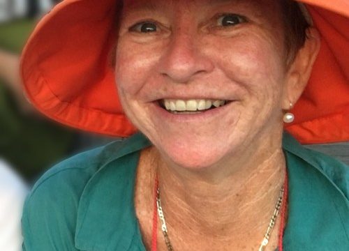 Jenine Mackay, smiling and wearing an orange hat and a teal blouse